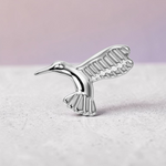 Instinct silver titanium hummingbird labret piercing with detailed wings and tail.