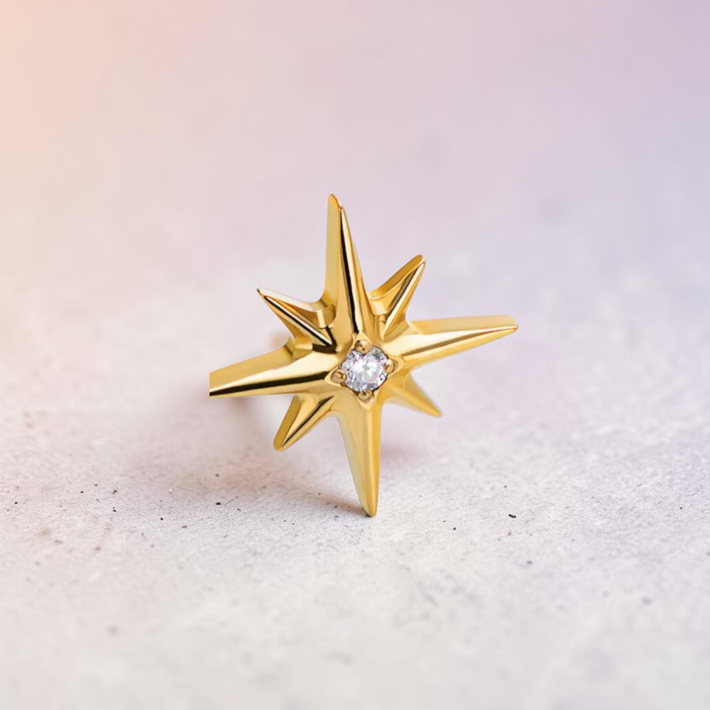 Instinct gold and silver titanium labret studs with a north star design and a central clear gem.