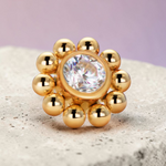 Instinct gold titanium labret piercing with internal thread, featuring a flower design with a clear crystal center and surrounding gold beads.