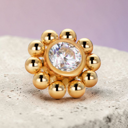 Instinct gold titanium labret piercing with internal thread, featuring a flower design with a clear crystal center and surrounding gold beads.
