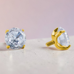 Instinct gold titanium labret piercing with clear, white opal, or green cubic zirconia stone.