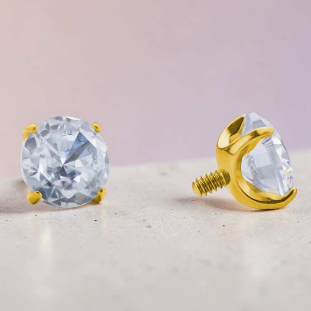 Instinct gold titanium labret piercing with clear, white opal, or green cubic zirconia stone.