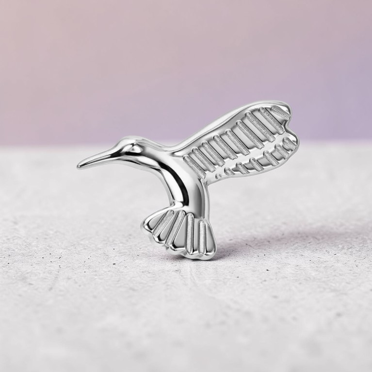 Instinct silver titanium hummingbird labret piercing with detailed wings and tail.